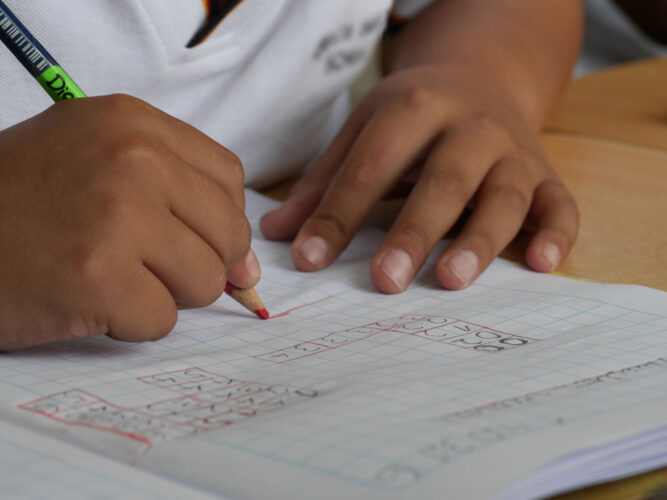 child hands writing in math notebook