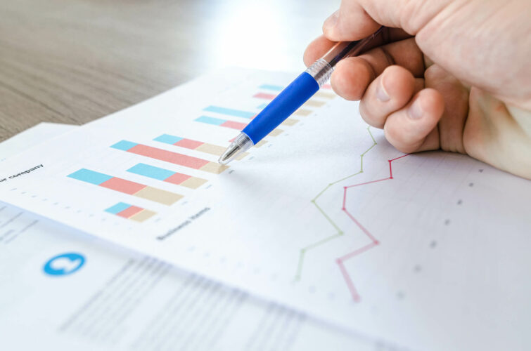 hand holding pen over charts and graphs